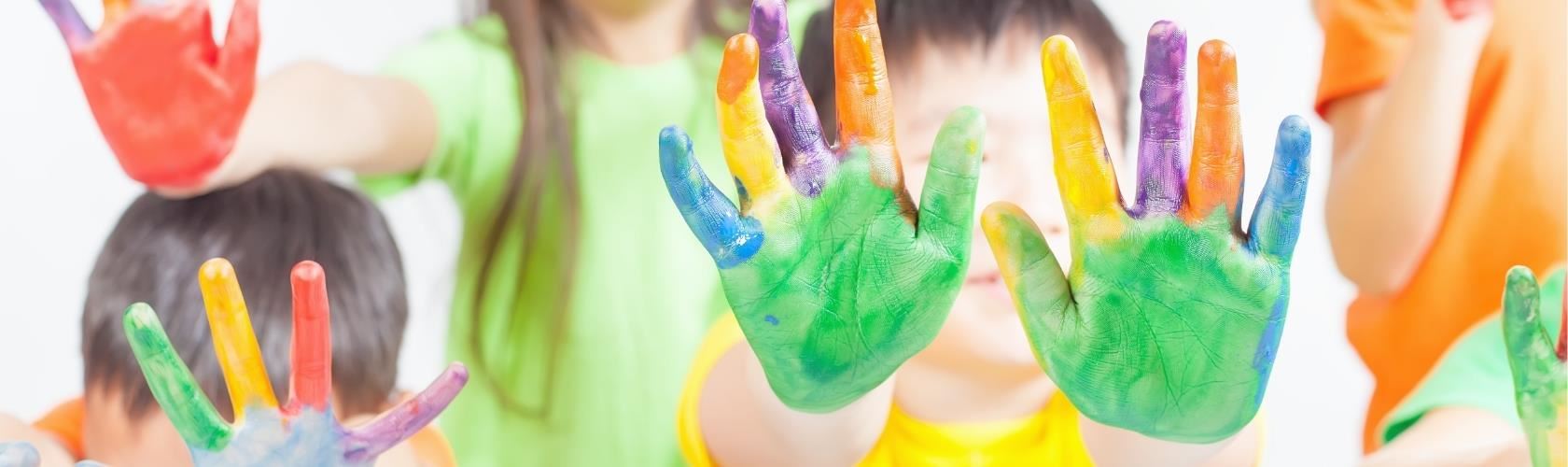 kids holding up their hands that are painted with different colors